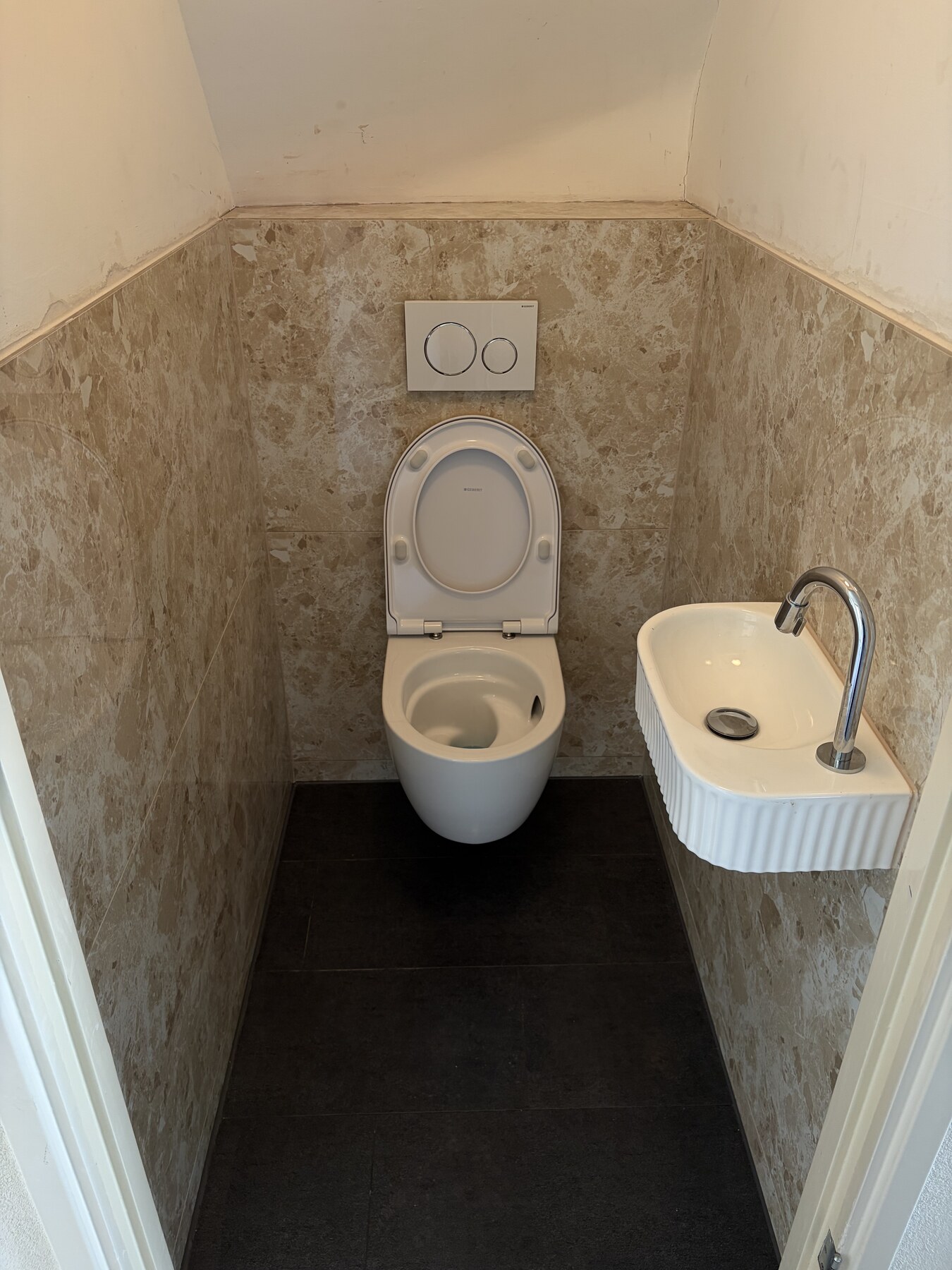 Toiletruimte met wastafel en betegelde achterwand
